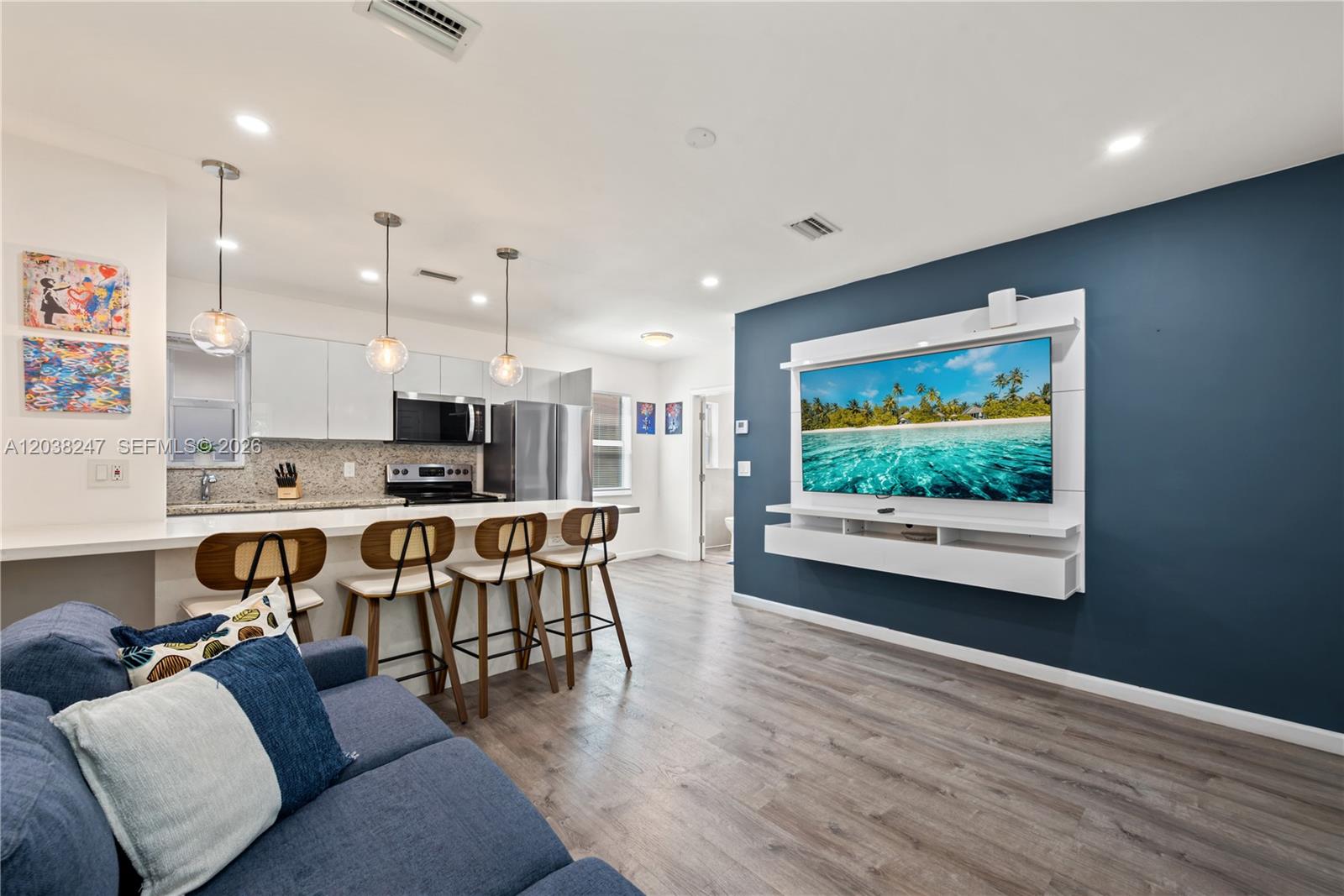 A modern open-concept living room and kitchen featuring a blue accent wall and stools — 329 SW 15th Ave, Miami FL 33135, MIAMI, FL