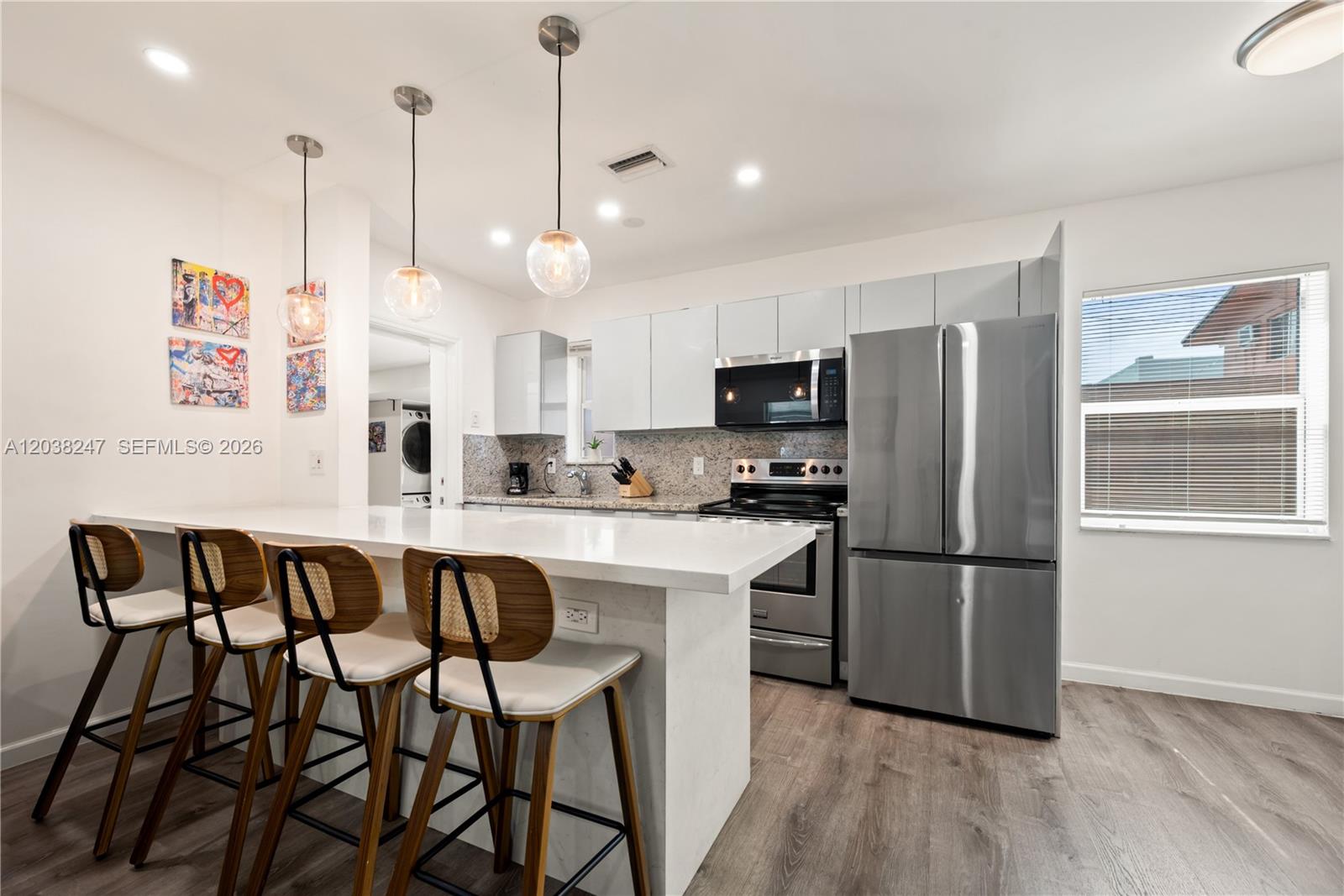 A modern kitchen features a white quartz island, stainless steel appliances, and four bar stools — 329 SW 15th Ave, Miami FL 33135, MIAMI, FL