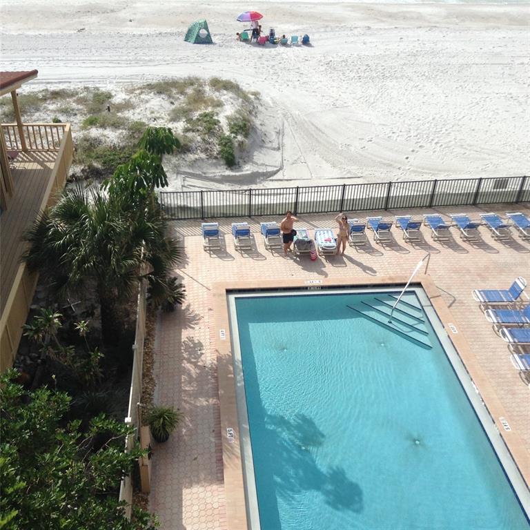 An elevated view of a swimming pool, lounge chairs, and a sandy beach with dunes — 14900 GULF BOULEVARD UNIT 113, MADEIRA BEACH, FL