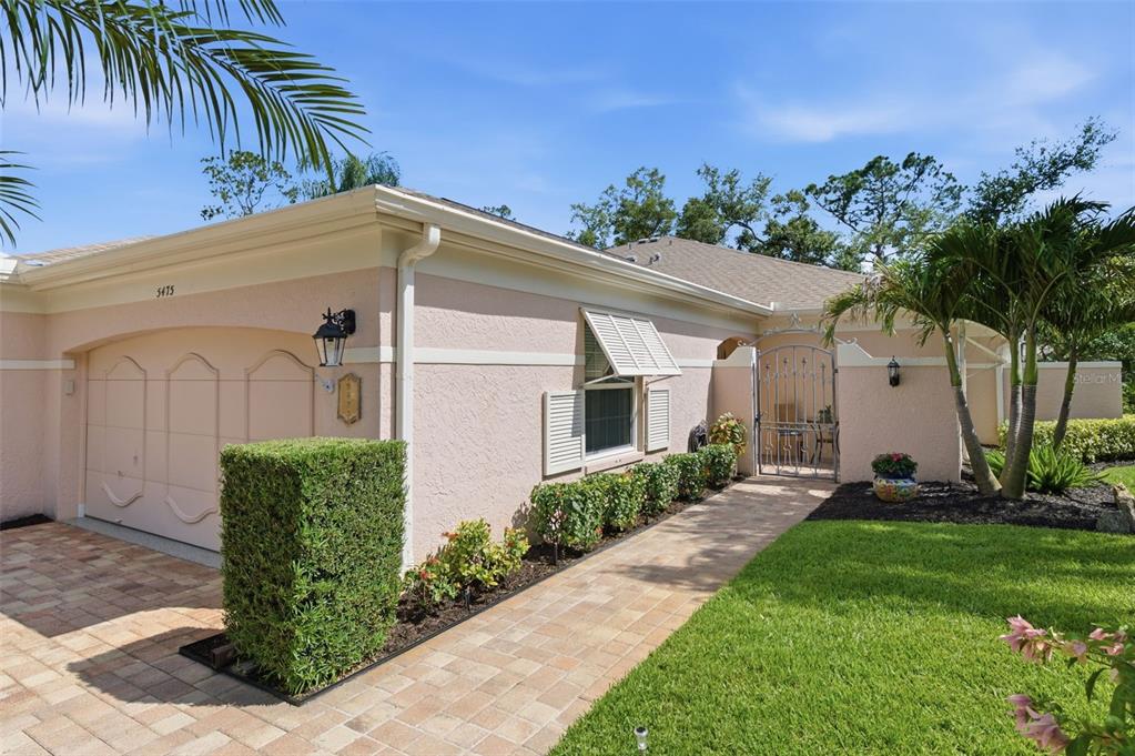 A single-story house with a beige stucco exterior, a paved walkway, and a garage — 5475 CHANTECLAIRE UNIT 58, SARASOTA, FL