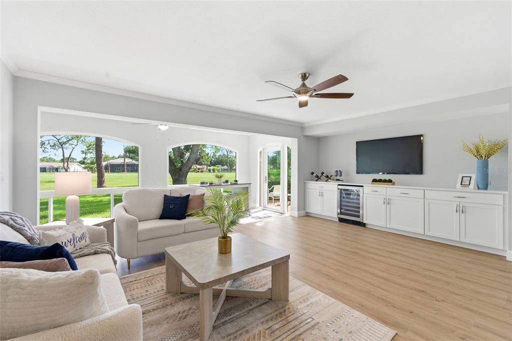 A living room features light wood flooring, white cabinetry, a wine cooler, and arched windows — 5475 CHANTECLAIRE UNIT 58, SARASOTA, FL