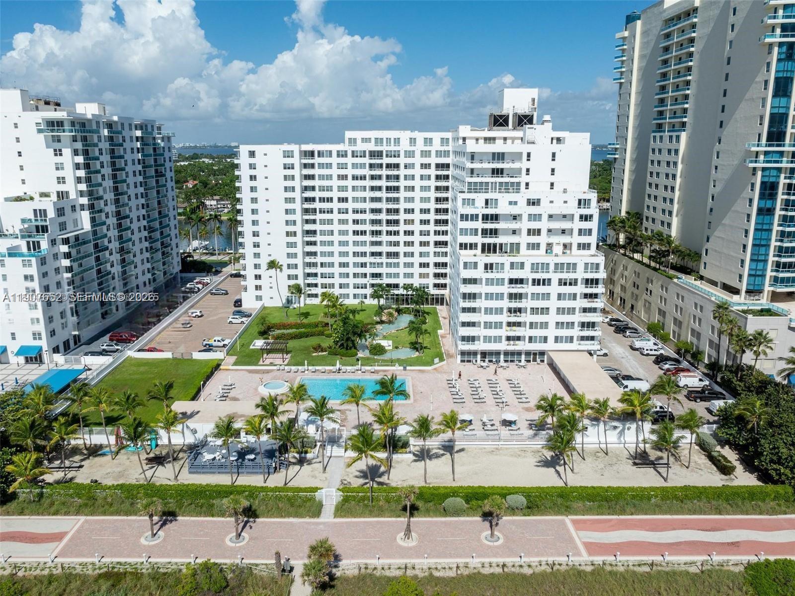 An aerial view shows white residential buildings with a central pool and landscaped courtyard — 5005 Collins Ave # 1523, Miami Beach FL 33140, MIAMI BEACH, FL