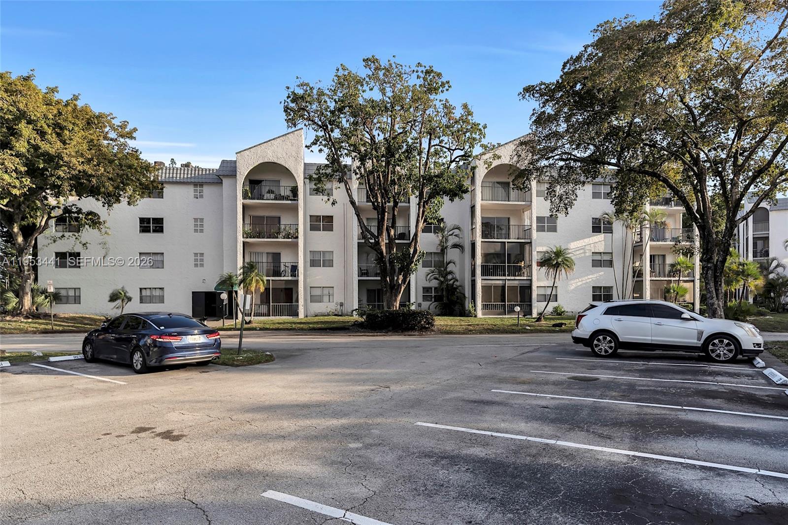 A multi-story apartment building with balconies and a parking lot in the foreground — 3300 Spanish Moss Ter # 106, Lauderhill FL 33319, LAUDERHILL, FL