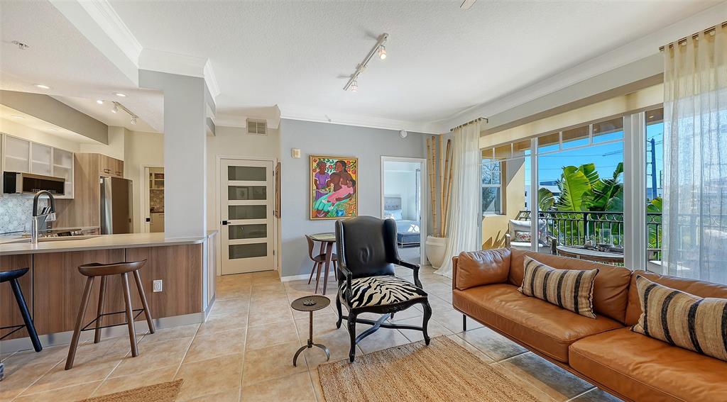 A living room with a leather sofa, zebra-print chair, and an adjacent kitchen with stools — 1268 11TH STREET UNIT 2403, SARASOTA, FL