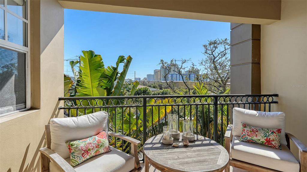A covered balcony features two armchairs, a round wooden table, and a metal railing — 1268 11TH STREET UNIT 2403, SARASOTA, FL
