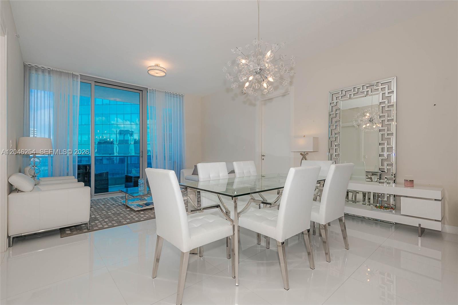 A modern dining room features a glass table, white chairs, and a large decorative mirror — 200 Biscayne Boulevard Way # 5109, Miami FL 33131, MIAMI, FL