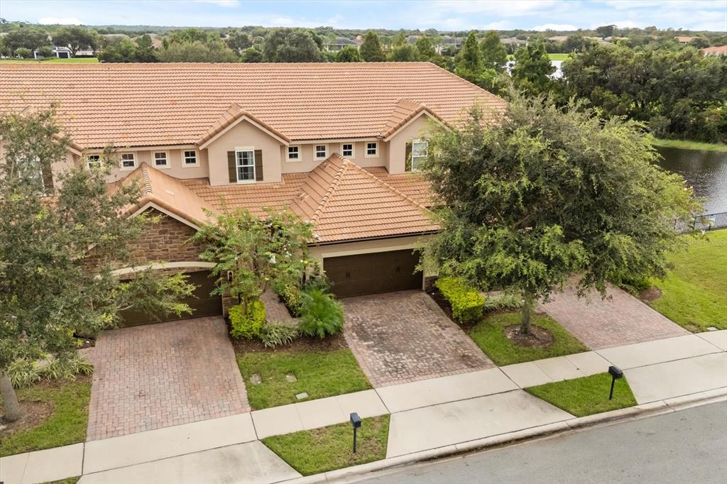 An aerial view of two attached townhomes with brown tile roofs and brick paver driveways — 10613 BELFRY CIRCLE, ORLANDO, FL
