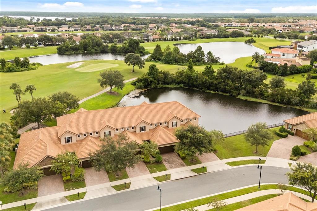 An aerial view shows a multi-unit residential building with a tile roof near a pond — 10613 BELFRY CIRCLE, ORLANDO, FL