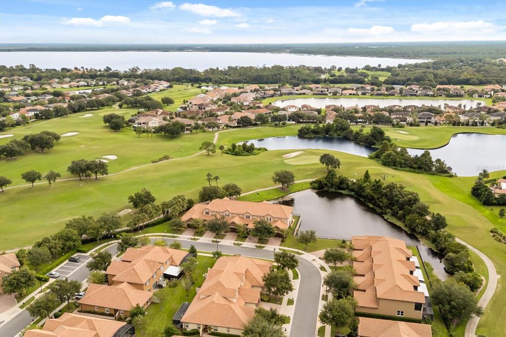 An aerial view shows residential townhomes with tile roofs situated along a golf course — 10613 BELFRY CIRCLE, ORLANDO, FL