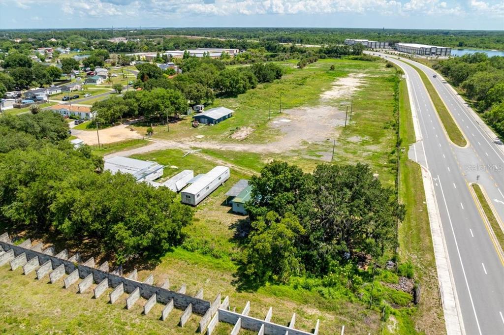 An aerial view shows a vacant lot with several small structures and a nearby highway — 4043 DANA KATHERINE DRIVE, KISSIMMEE, FL