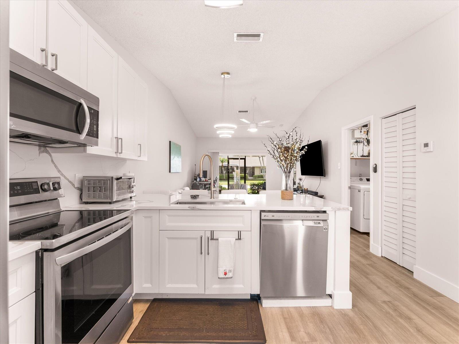 A modern kitchen features white cabinets, stainless steel appliances, and a quartz-topped island — 18861 Argosy Drive, Boca Raton FL 33496, BOCA RATON, FL