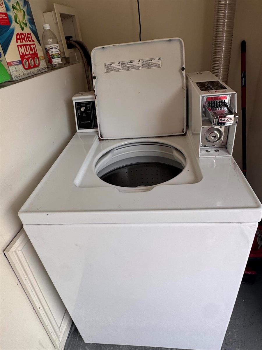 A white coin-operated top-loading washing machine sits in a laundry area — 570 NE 64th Street Unit 2, Miami FL 33138, MIAMI, FL