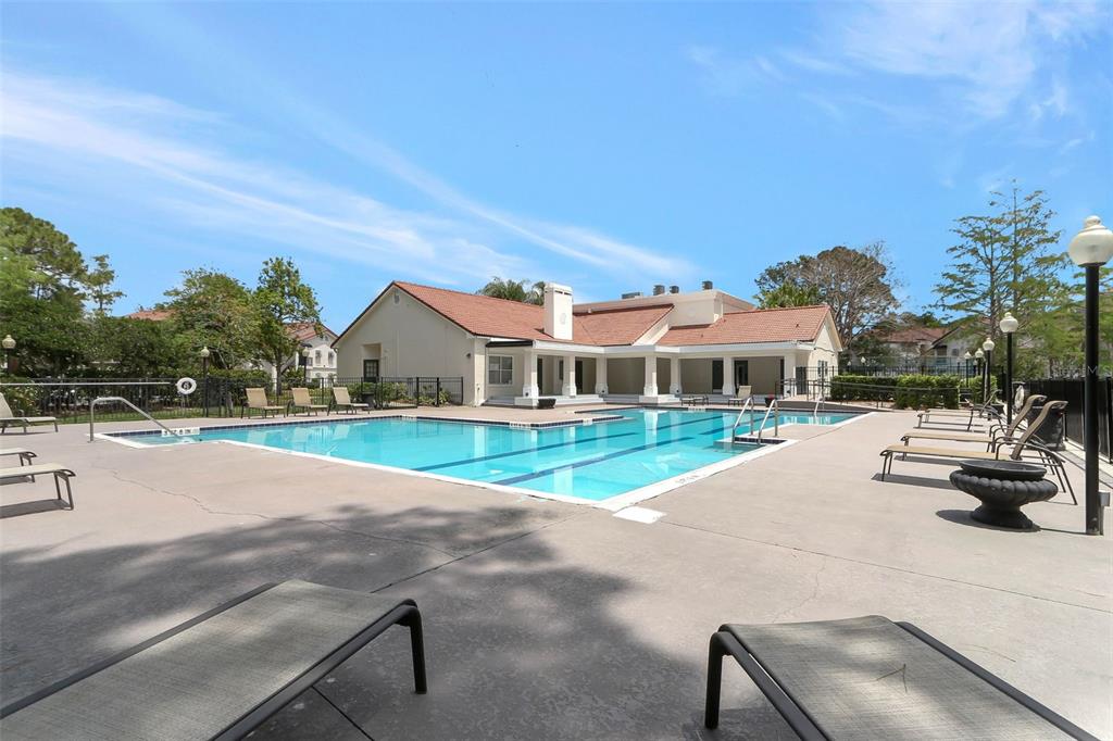 A rectangular swimming pool sits on a concrete deck in front of a clubhouse building — 5160 CONROY ROAD UNIT 21, ORLANDO, FL