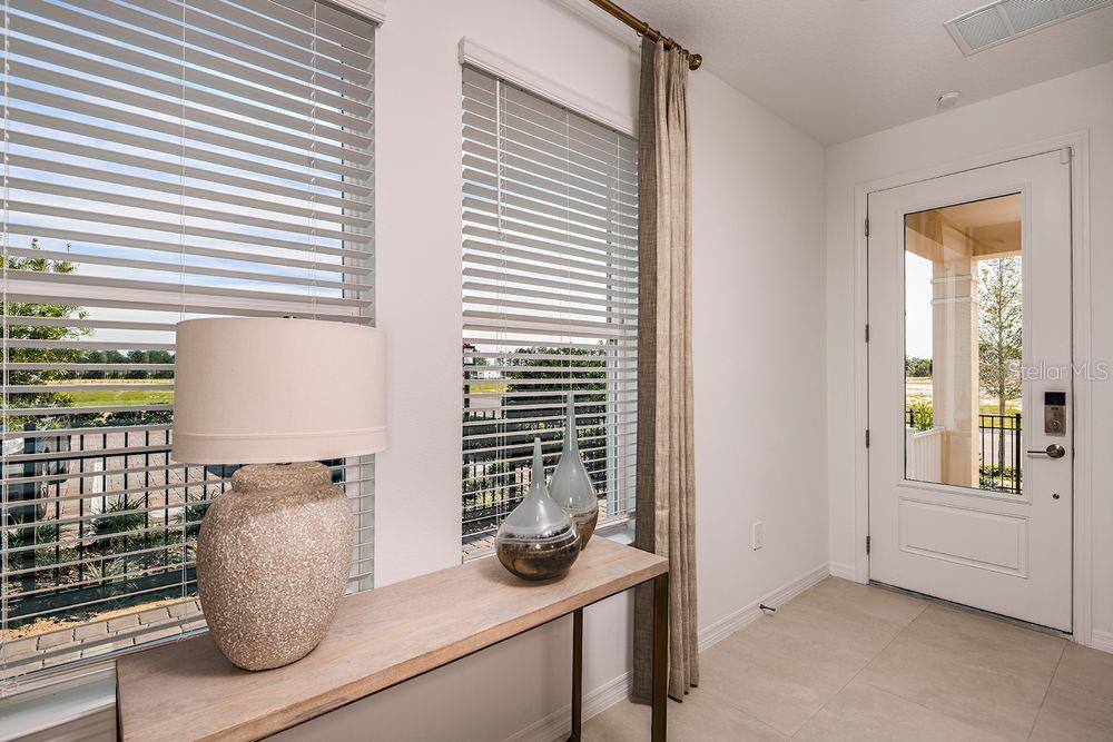 A bright entryway features a console table, lamp, decorative vases, and a glass-paneled front door — 14784 FIELD DAISY DRIVE, WINTER GARDEN, FL