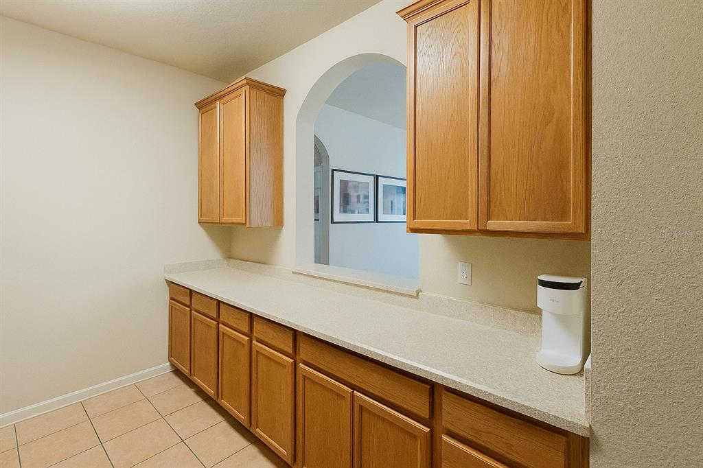 A kitchen area features light wood cabinets, a long beige countertop, and an arched pass-through window — 3326 ROBERT TRENT JONES DRIVE UNIT 10402, ORLANDO, FL