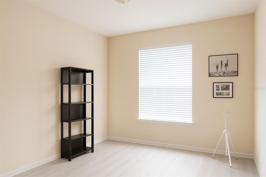 An empty room features light-colored walls, wood-look flooring, a black bookshelf, and a window — 3326 ROBERT TRENT JONES DRIVE UNIT 10402, ORLANDO, FL