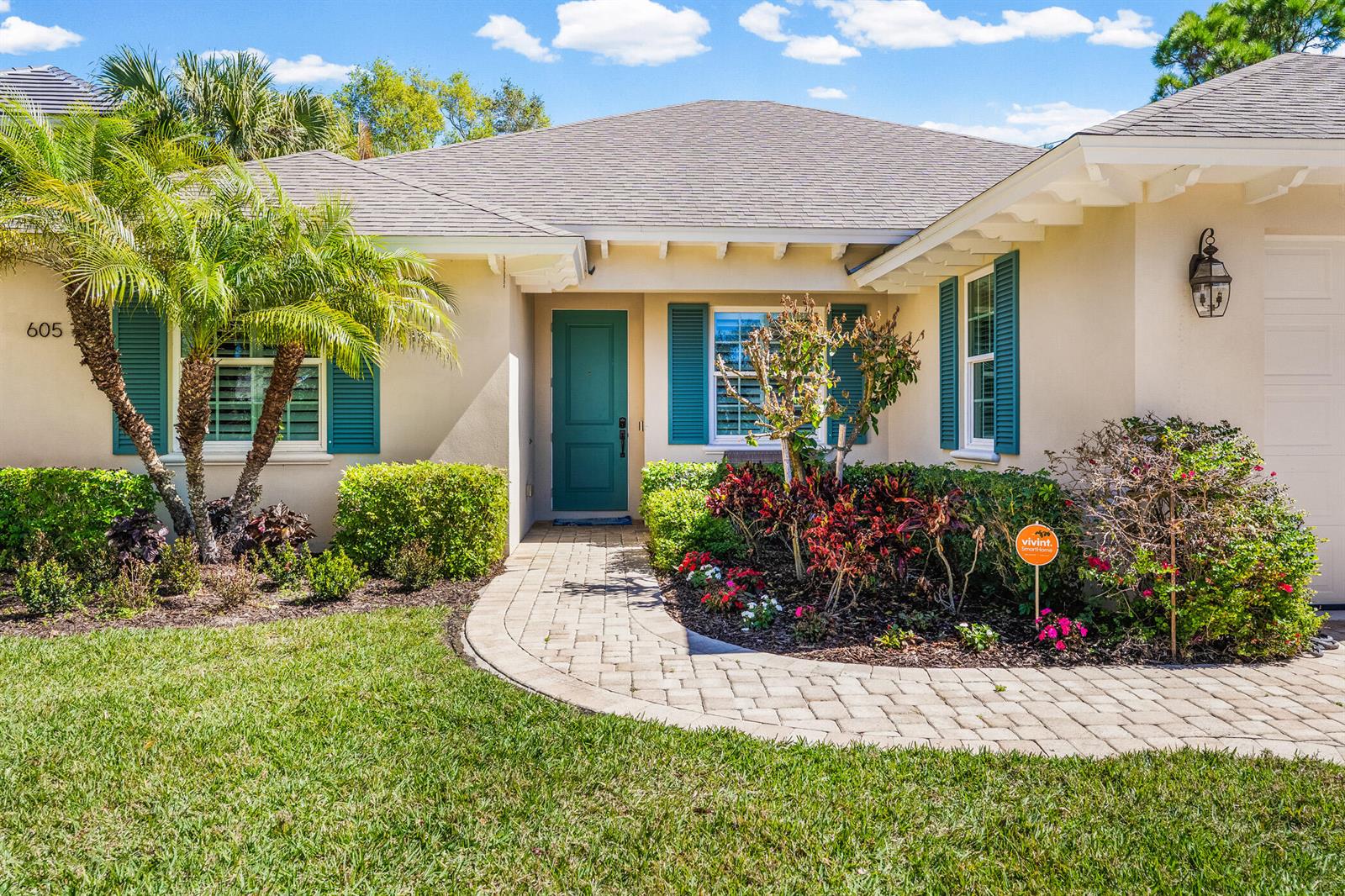 A single-story house with a teal front door, green shutters, and a paved walkway — 605 Bridgewater Lane SW, Vero Beach FL 32962, VERO BEACH, FL