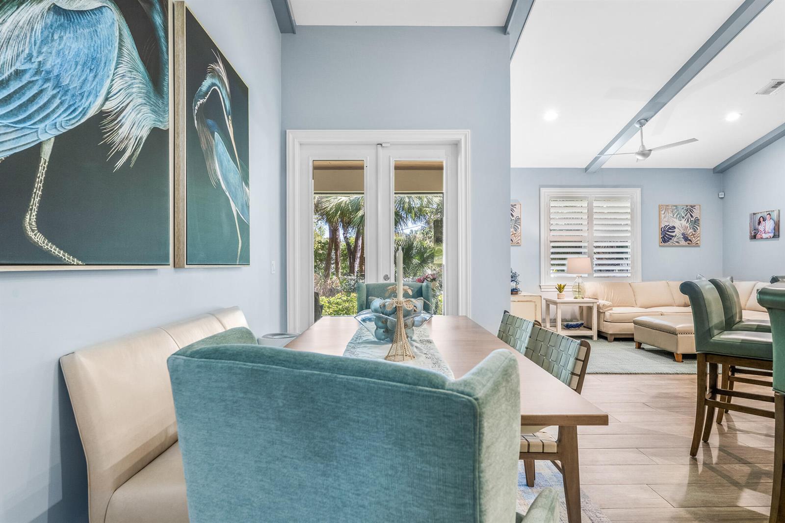 A dining area with a wooden table, teal chairs, and a bench faces glass doors — 605 Bridgewater Lane SW, Vero Beach FL 32962, VERO BEACH, FL
