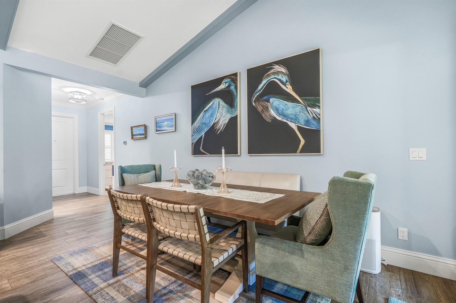 A dining room features a wooden table, woven chairs, a bench, and large bird artwork — 605 Bridgewater Lane SW, Vero Beach FL 32962, VERO BEACH, FL