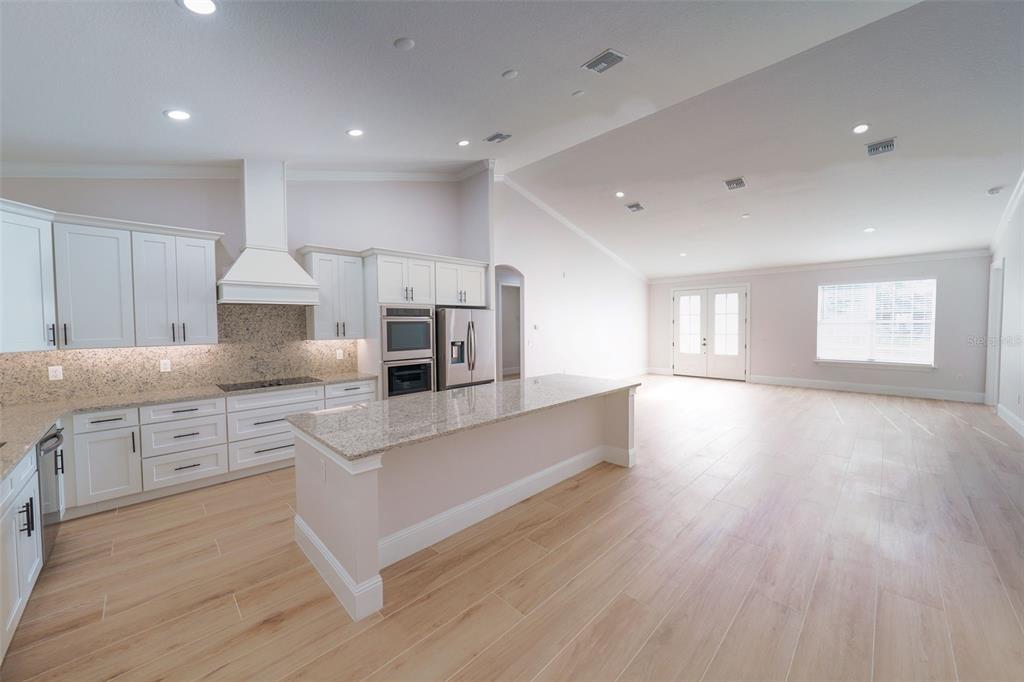 A modern kitchen with white cabinets and granite countertops opens into a spacious living area — 16324 SE 88TH AVENUE, SUMMERFIELD, FL