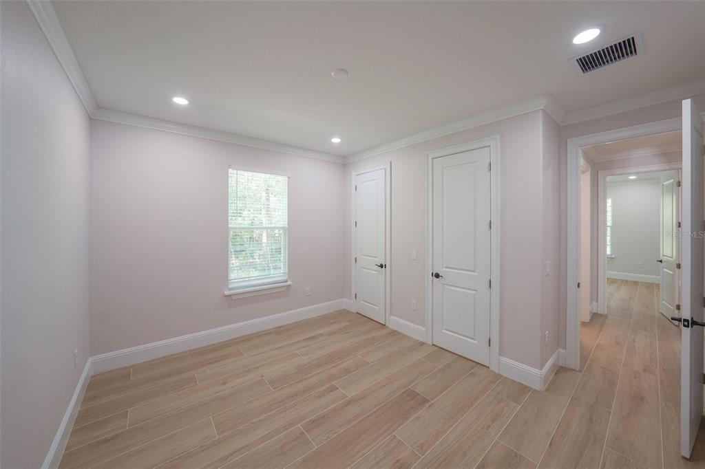 An empty room with light-colored walls, wood-look tile flooring, two interior doors, and a window — 16324 SE 88TH AVENUE, SUMMERFIELD, FL