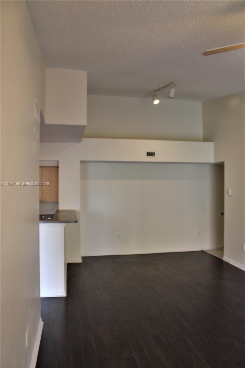 An interior view shows a living area with dark wood flooring and a kitchen counter — 2400 E Preserve Way # 304, Miramar FL 33025, MIRAMAR, FL