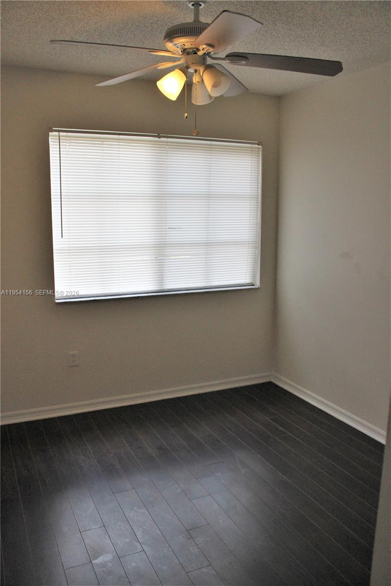 An empty bedroom features dark wood-look flooring, light gray walls, and a ceiling fan — 2400 E Preserve Way # 304, Miramar FL 33025, MIRAMAR, FL