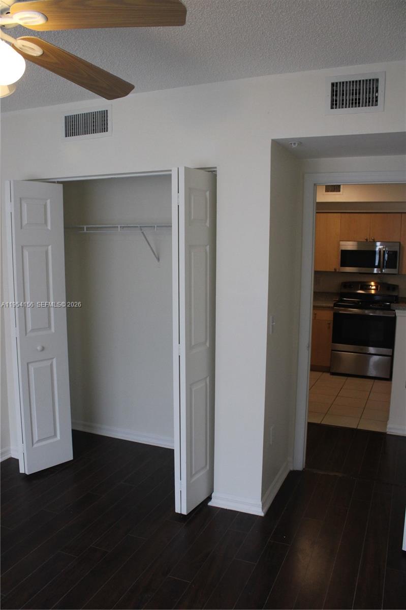 A room features dark wood flooring, a white closet with open doors, and a ceiling fan — 2400 E Preserve Way # 304, Miramar FL 33025, MIRAMAR, FL