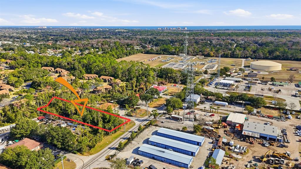An aerial view shows a rectangular wooded lot outlined in red next to industrial buildings — 19 UTILITY DRIVE, PALM COAST, FL