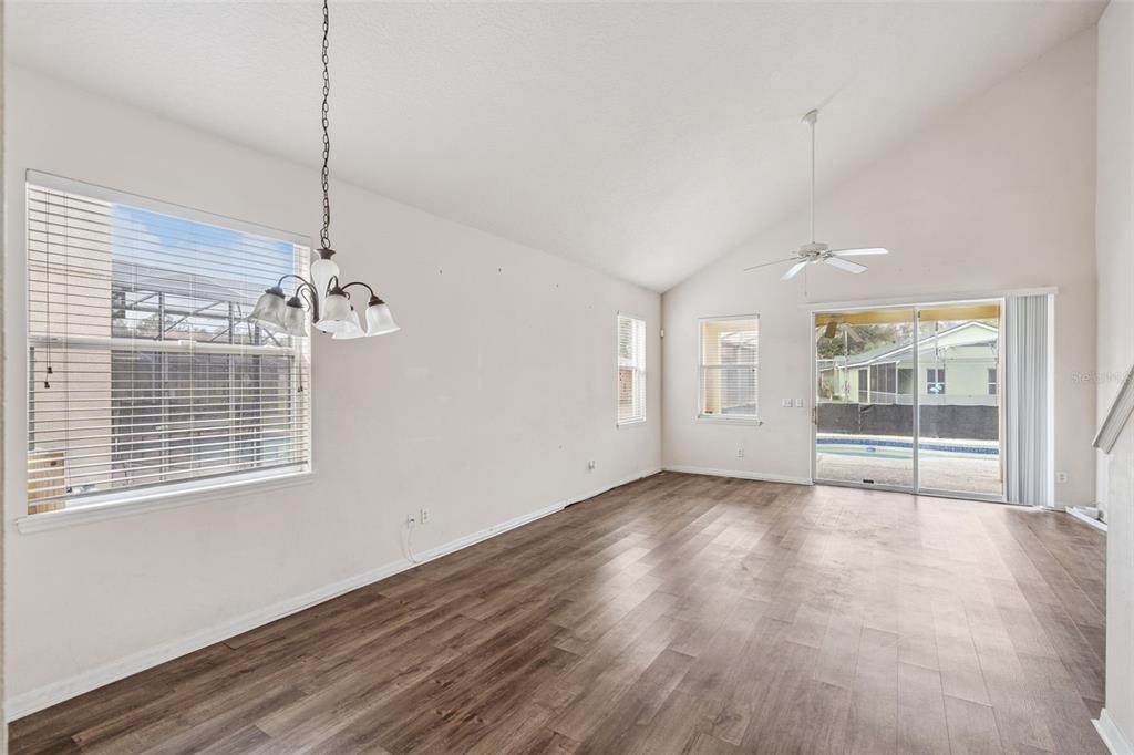 An empty room with wood-look flooring, a vaulted ceiling, a ceiling fan, and sliding doors — 1755 ROYAL RIDGE DRIVE, DAVENPORT, FL