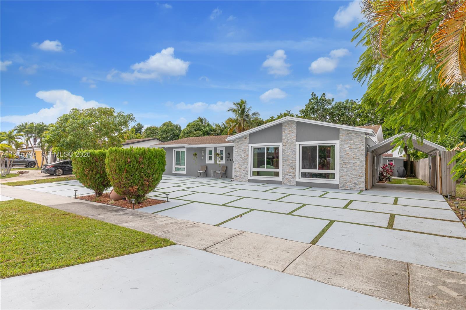 A single-story house with a gray facade, stone accents, and a large paved driveway — 15244 SW 108th Ct, Miami FL 33157, MIAMI, FL