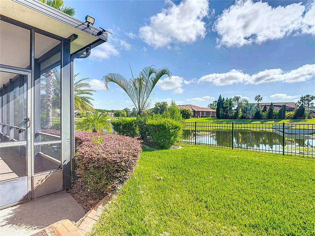 A screened-in porch overlooks a grassy backyard, a metal fence, and a pond — 772 SAN RAPHAEL STREET, KISSIMMEE, FL