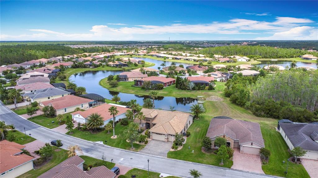 An aerial view shows a suburban neighborhood with houses surrounding a central lake — 772 SAN RAPHAEL STREET, KISSIMMEE, FL