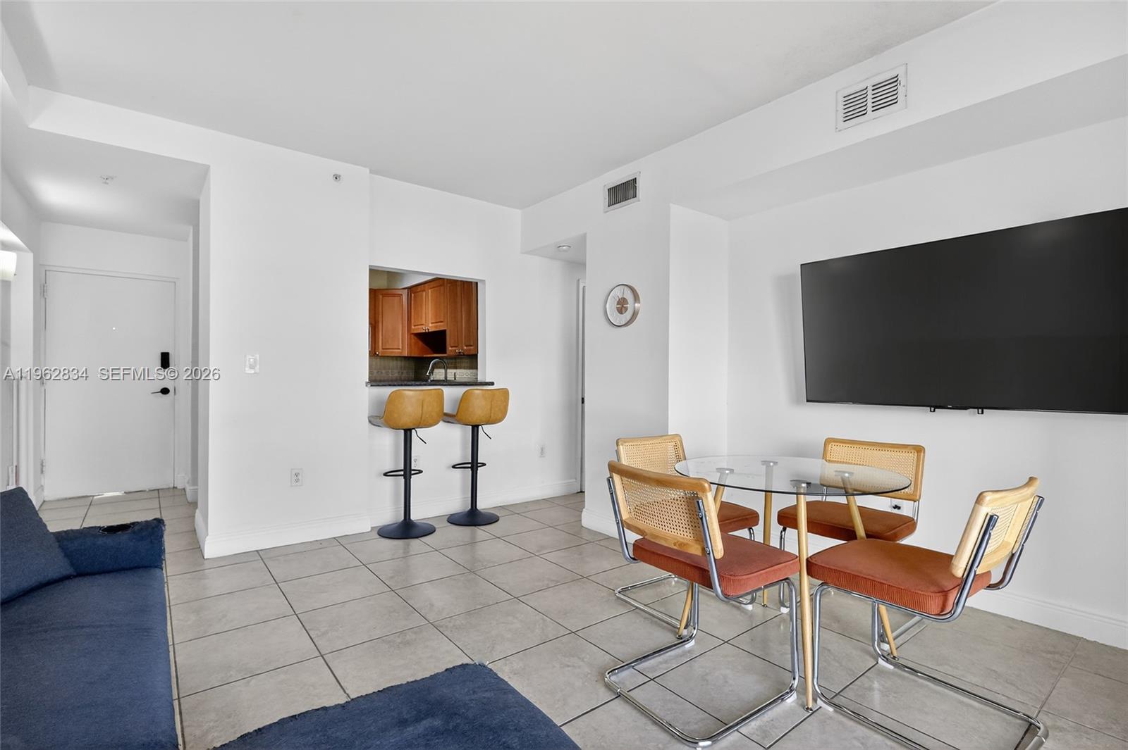 A living and dining area features tile floors, a breakfast bar, and a wall-mounted television — 134 SW 7th Ave # 404, Miami FL 33130, MIAMI, FL