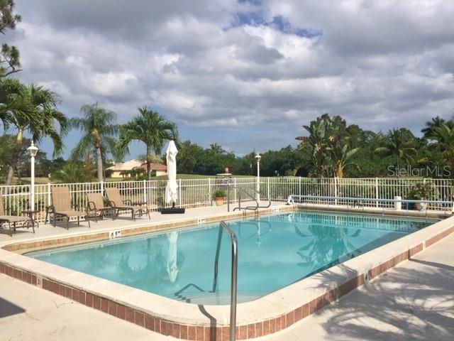 A rectangular swimming pool is surrounded by a white fence and lounge chairs outdoors — 801 ISLAMORADA BOULEVARD UNIT 26C, PUNTA GORDA, FL