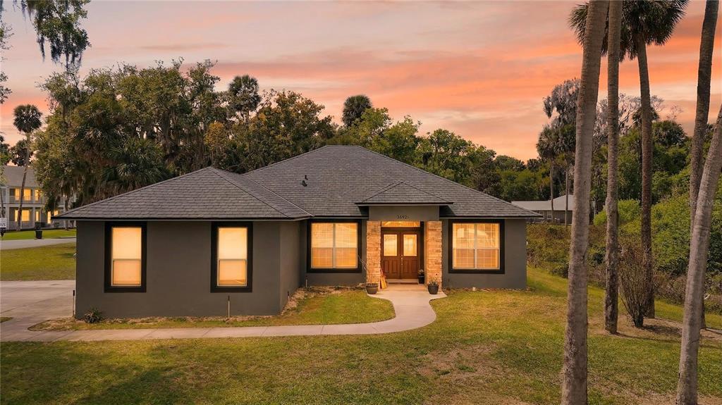 A single-story house with a dark gray exterior, stone entryway, and a hip roof — 28931 BEAUCLAIRE DRIVE, TAVARES, FL