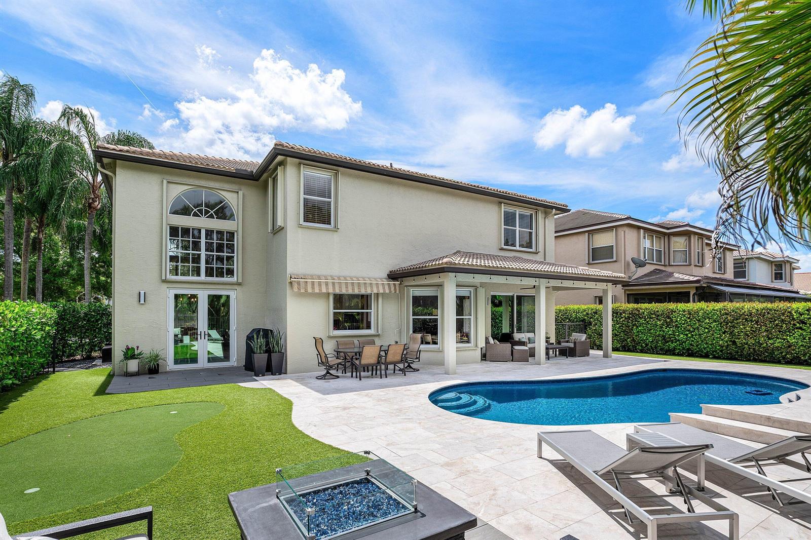 A two-story house exterior features a backyard pool, patio, fire pit, and putting green — 19453 Estuary Drive, Boca Raton FL 33498, BOCA RATON, FL