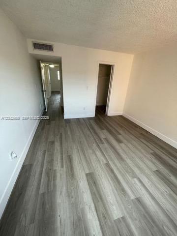 A bedroom with light gray wood-look flooring, white walls, and an open closet door — 6125 W 20th Ave # 312, Hialeah FL 33012, HIALEAH, FL
