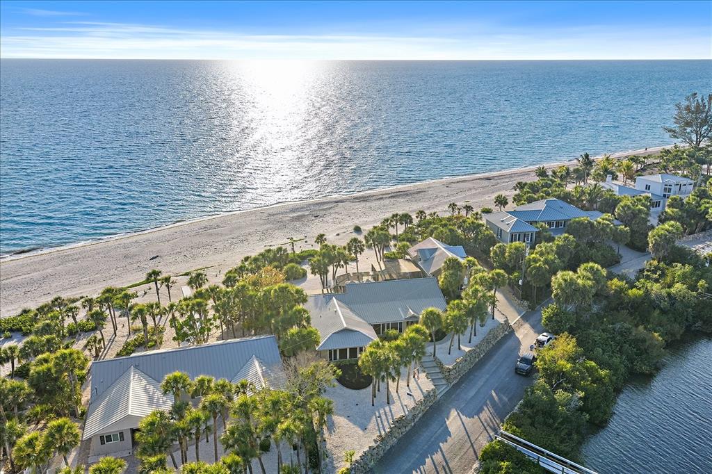 An aerial view shows beachfront houses nestled among palm trees along a coastal road — 756 N MANASOTA KEY ROAD, ENGLEWOOD, FL