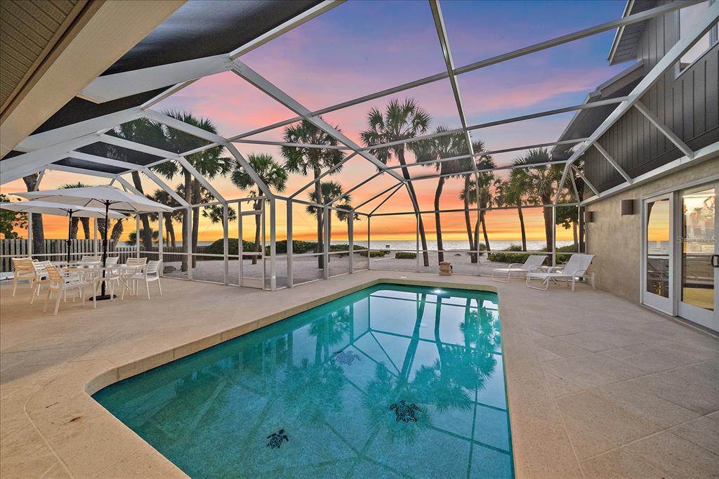 A screened-in pool patio overlooks a sandy beach and ocean at sunset — 756 N MANASOTA KEY ROAD, ENGLEWOOD, FL