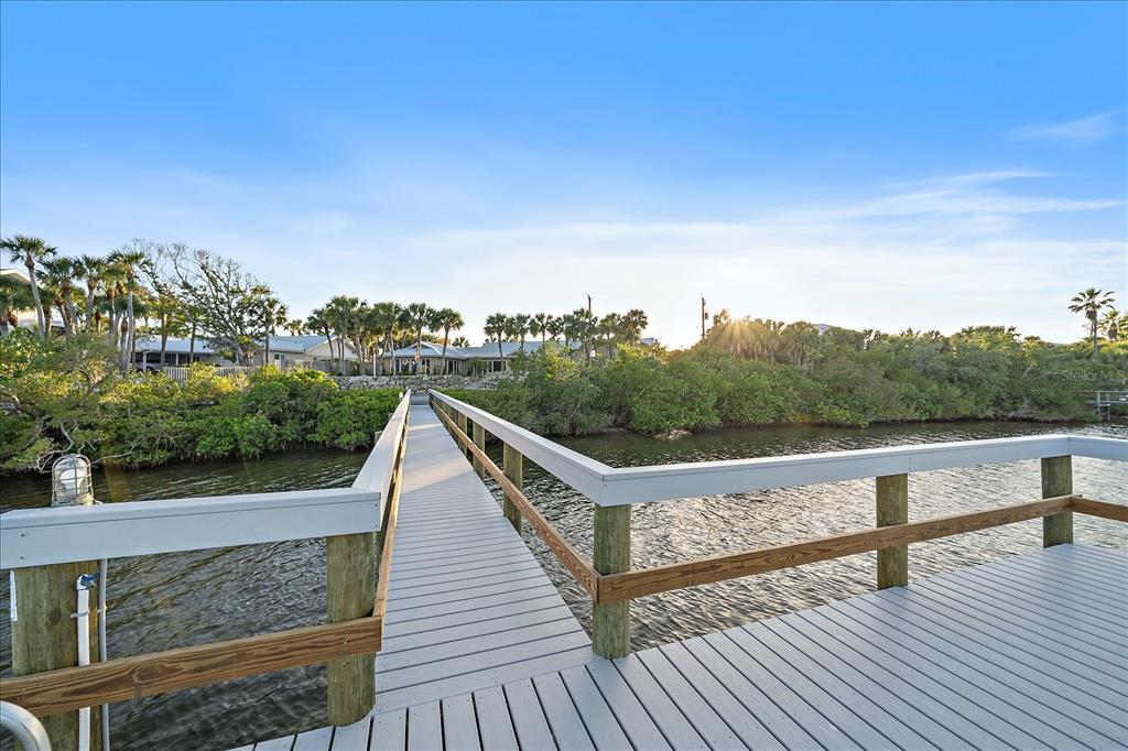 A wooden dock extends over the water toward a line of trees and houses — 756 N MANASOTA KEY ROAD, ENGLEWOOD, FL