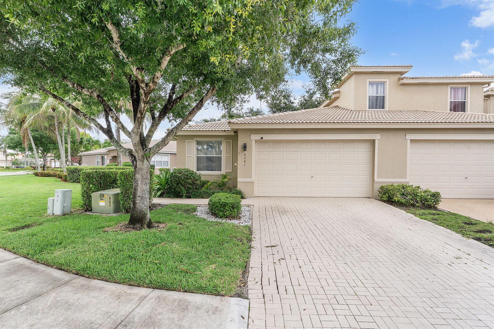 A beige single-story house with a paved walkway, a garage, and a small fenced yard — 8541 Water Cay, West Palm Beach FL 33411, WEST PALM BEACH, FL