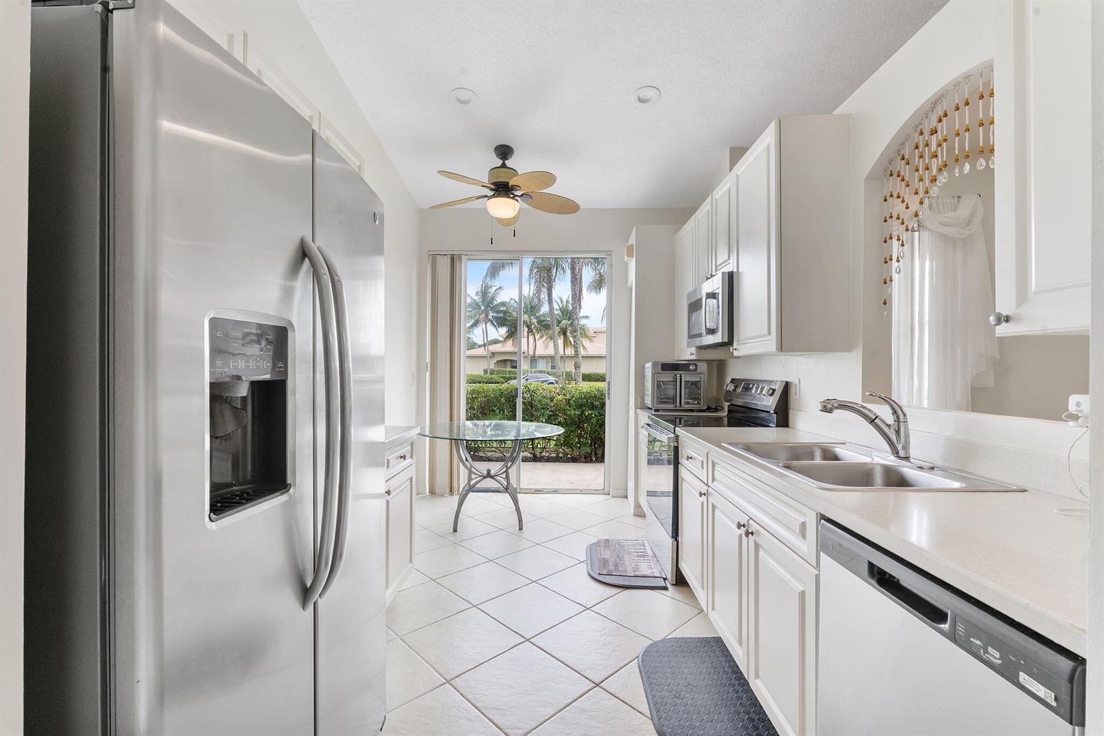 A living room features a gray sectional, brown leather sofas, and a wall-mounted television — 8541 Water Cay, West Palm Beach FL 33411, WEST PALM BEACH, FL