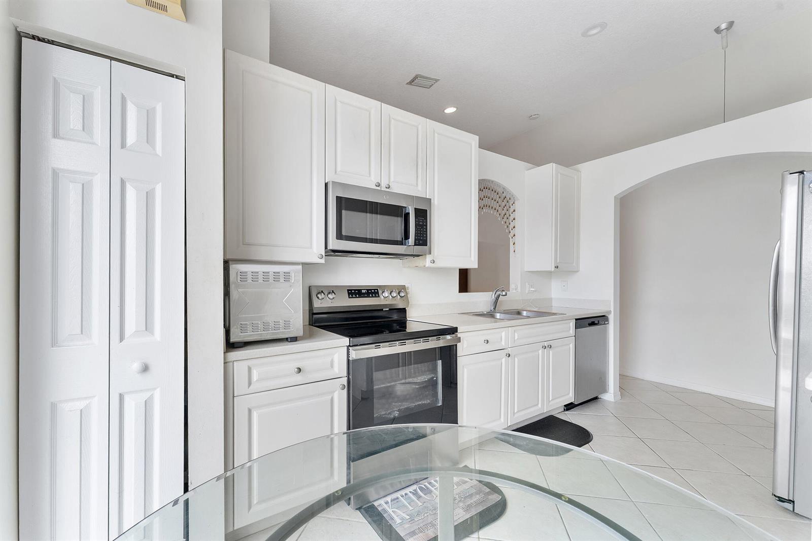 A dining room features a wooden table, four chairs, a chandelier, and an orange wall — 8541 Water Cay, West Palm Beach FL 33411, WEST PALM BEACH, FL
