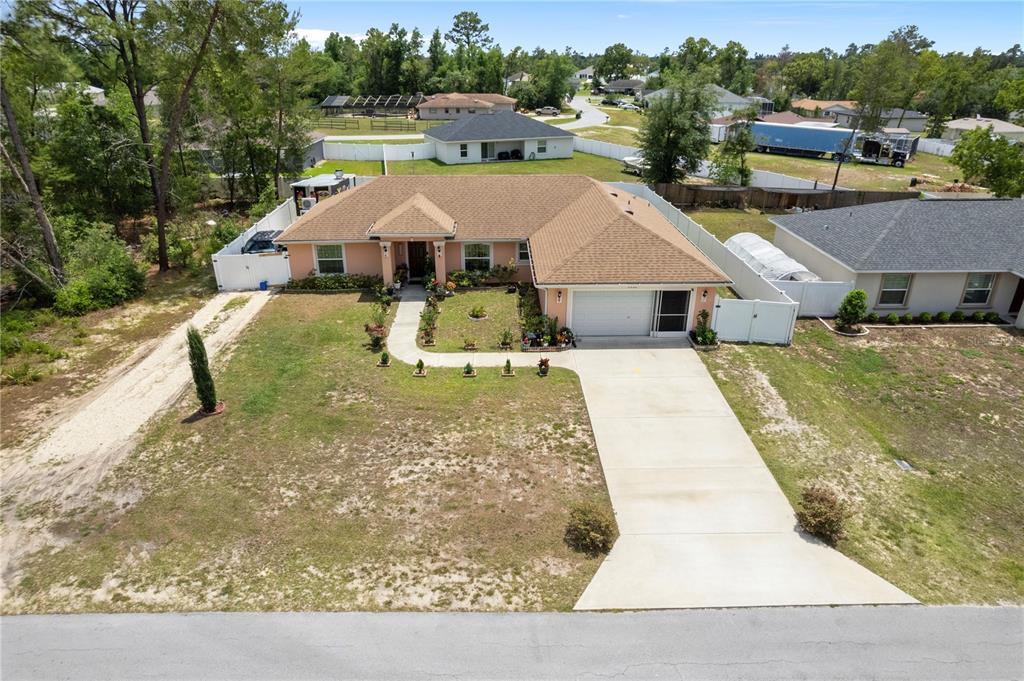 An aerial view shows a single-story house with a tan roof, peach exterior, and concrete driveway — 4406 SW 152ND STREET SW, OCALA, FL