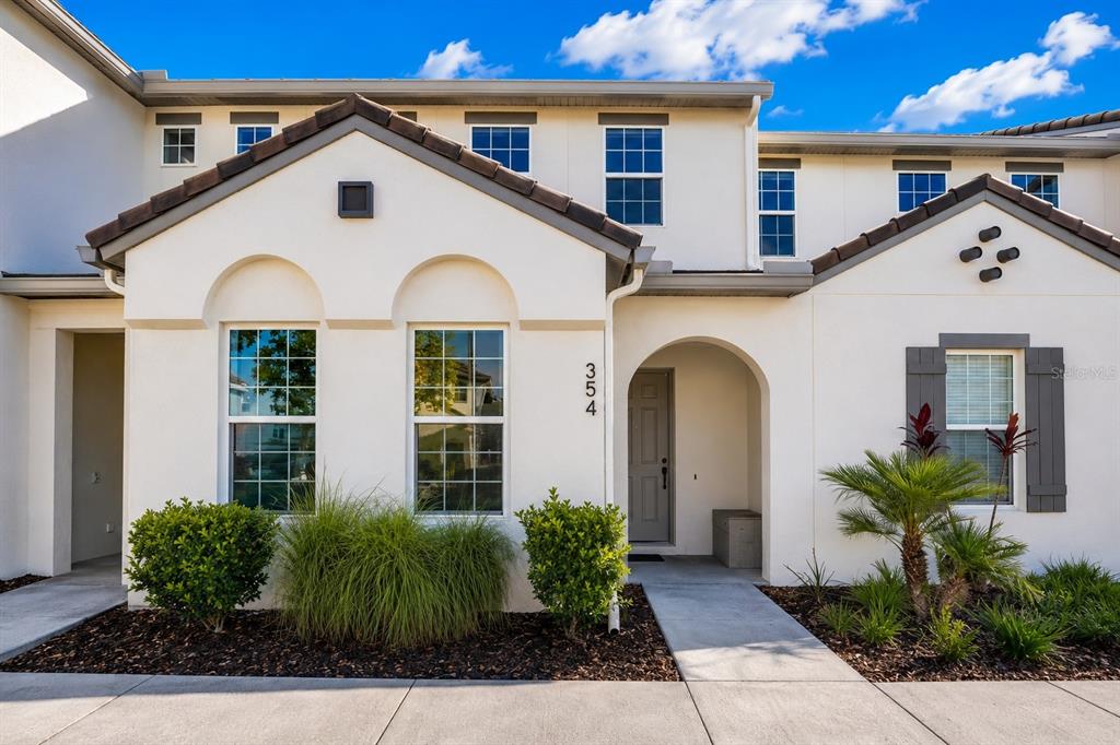 A two-story townhouse exterior features a beige stucco facade, arched windows, and a front entrance — 354 CAPTIVA DRIVE, DAVENPORT, FL