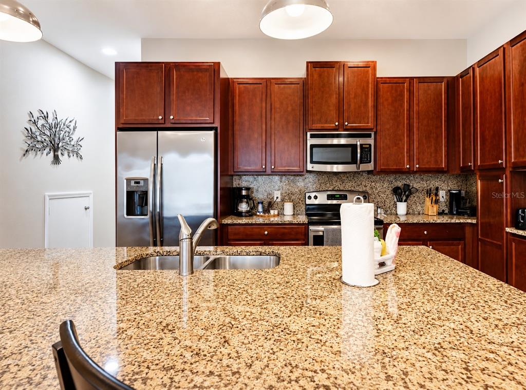 A kitchen features dark wood cabinets, granite countertops, stainless steel appliances, and a central island — 354 CAPTIVA DRIVE, DAVENPORT, FL
