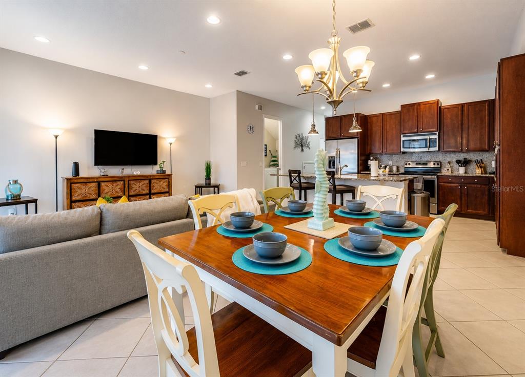 A dining area with a wooden table and chairs sits adjacent to an open kitchen — 354 CAPTIVA DRIVE, DAVENPORT, FL