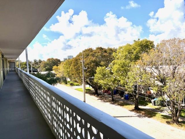 A view from a covered balcony overlooking a street lined with trees and buildings — 1425 Arthur St # 403A, Hollywood FL 33020, HOLLYWOOD, FL