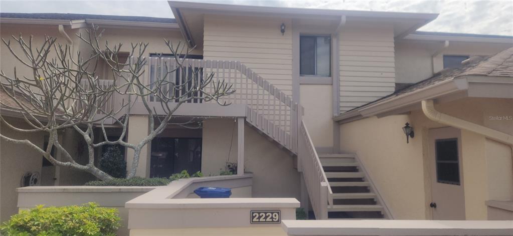 An exterior view of a two-story townhouse with a wooden staircase and a balcony — 2229 PARKLAKE POINT UNIT G7, VENICE, FL